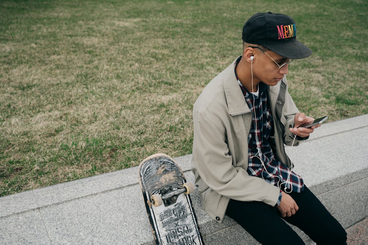 A Man in Gray Jacket Sitting on the Street while Listening to Music